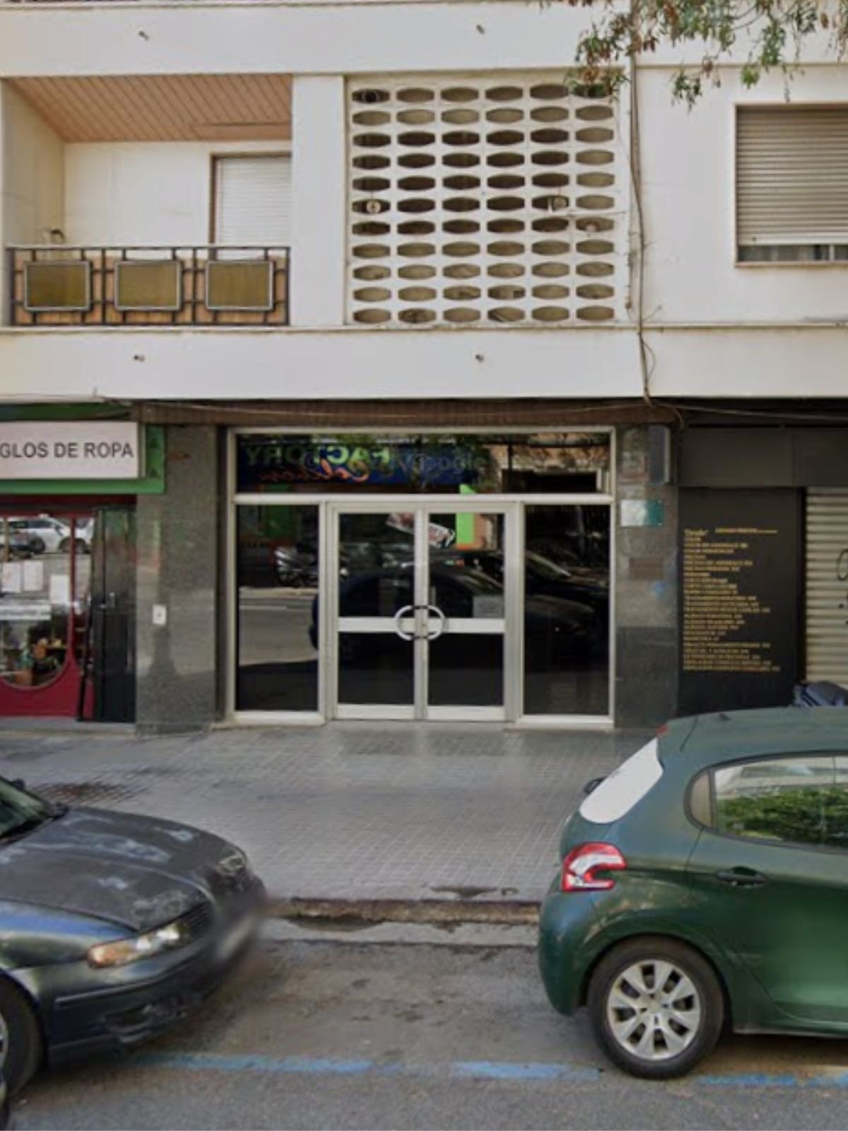 Fachada del edificio en la calle Centelles, con la puerta acristalada de entrada entre dos locales comerciales